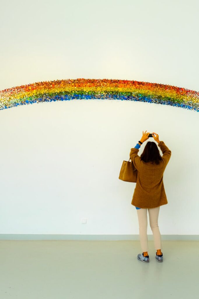 pexels-photo-673649-673649 A woman stands observing a colorful rainbow art installation indoors.
